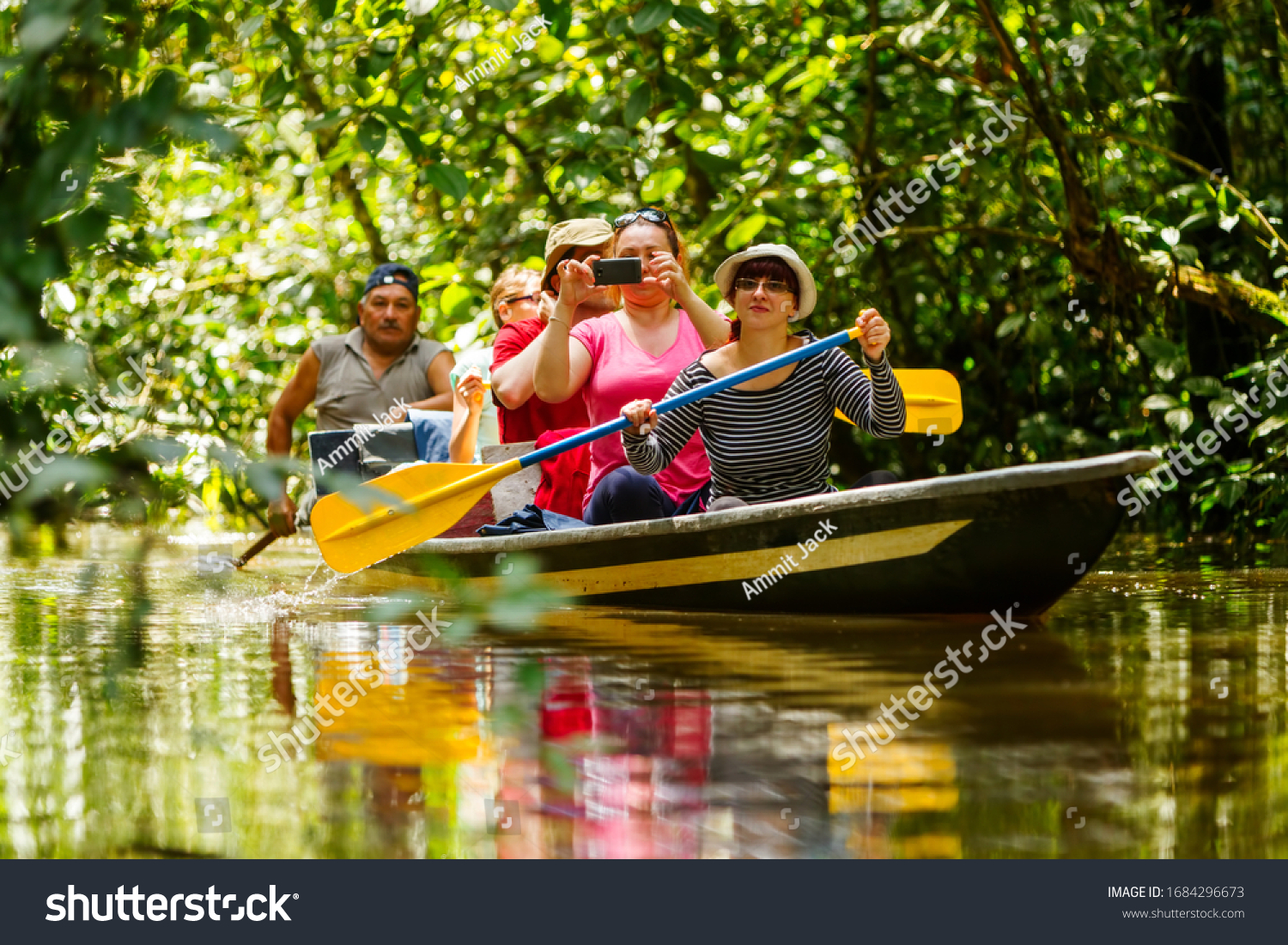 A group of tourists on a boat in the Amazon jungle, fishing and exploring the river while surrounded by lush wildlife and a vibrant community. #1684296673