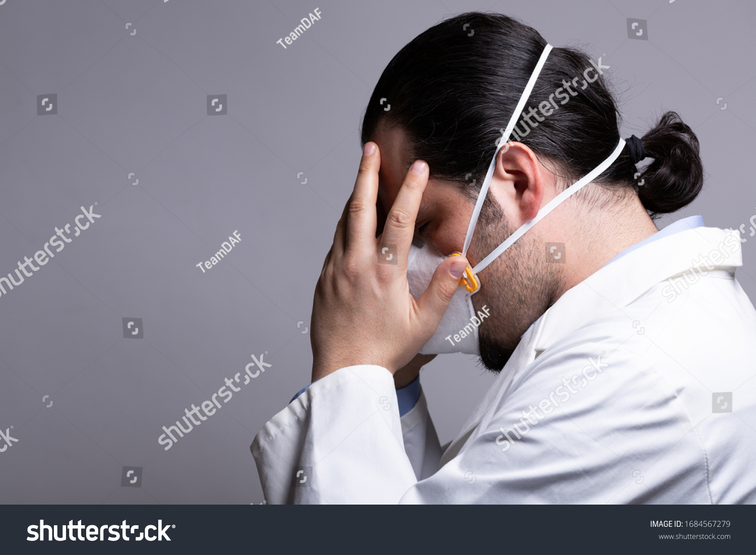 Frustrated medical doctor wearing a respiratory mask  touching his head with his hands. Burnout and medicine crisis concept. #1684567279