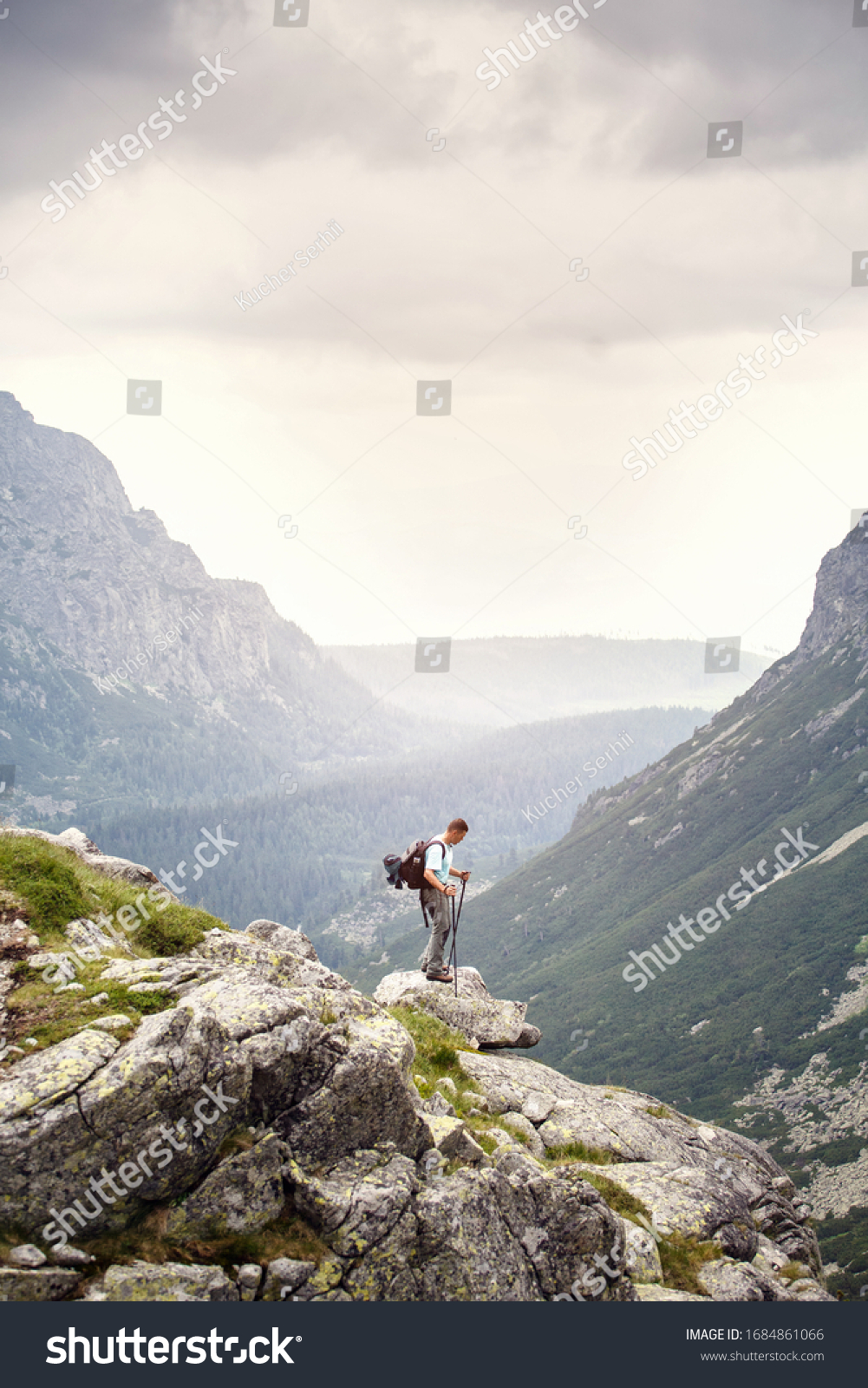 Hiker with backpack standing on top of a mountain. Lifestyle success concept adventure active vacations outdoor happiness freedom emotions. High Tatras mountains. #1684861066