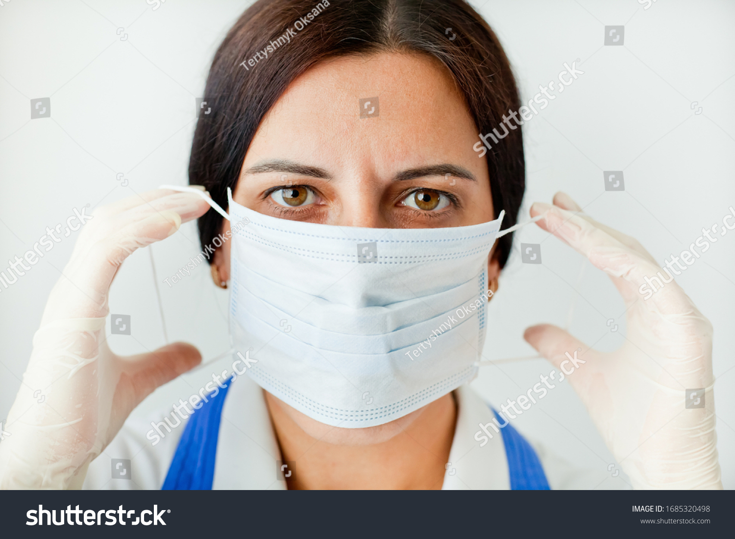 Tired, beautiful female doctor in a protective mask looks at us close-up. Protection against coronavirus Covid-19. #1685320498