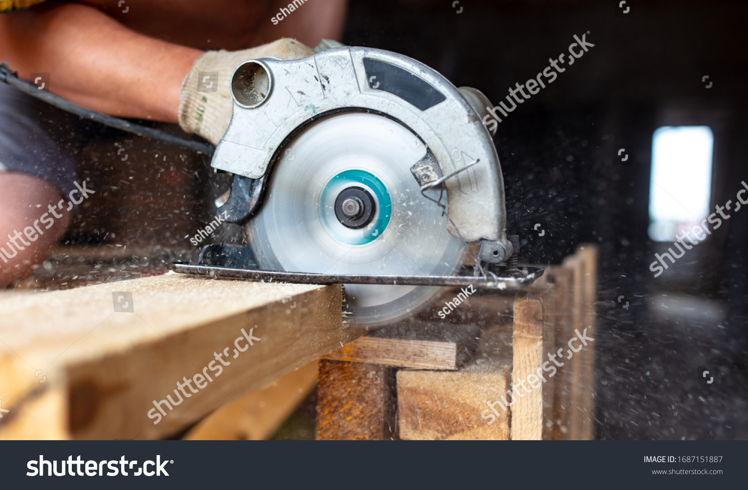 A worker saws a wooden beam. Building a house. #1687151887