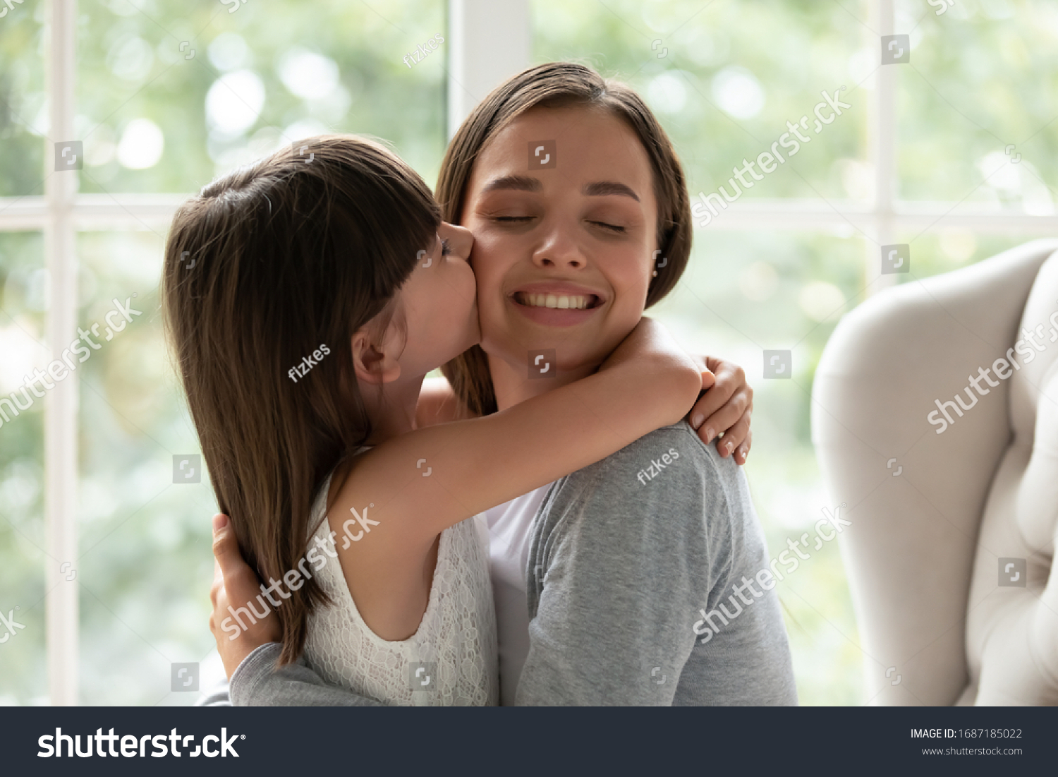 Cute little girl child kiss on cheek overjoyed young mother or nanny show love and care, small preschooler daughter cuddle hug happy mom, feel grateful and thankful, family bonding, unity concept #1687185022