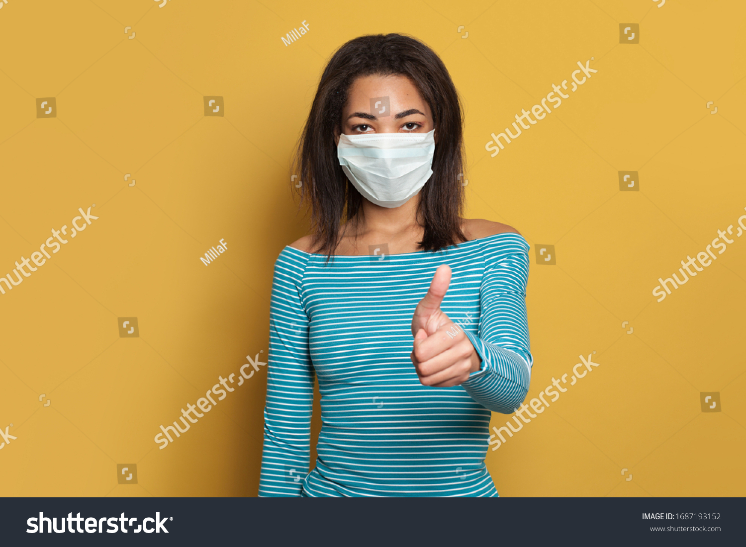 Black African American woman in face mask showing thumb up on yellow background #1687193152