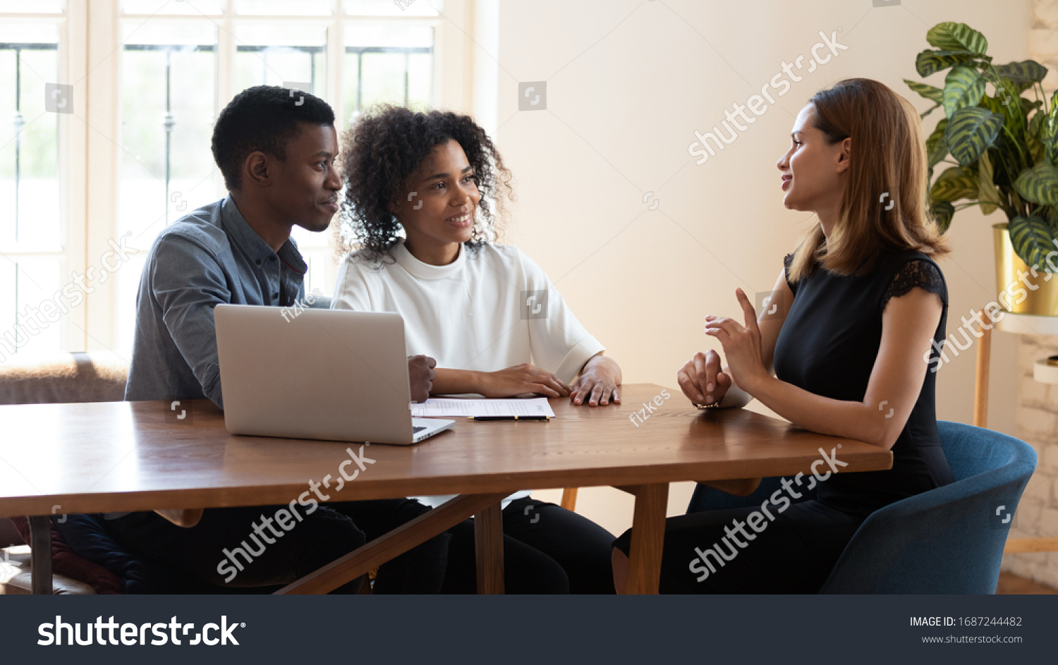 Female broker makes offer to young African ethnicity married couple during meeting in company office. Family taking loan in bank, listening advisor, real estate agent and customers negotiating concept #1687244482