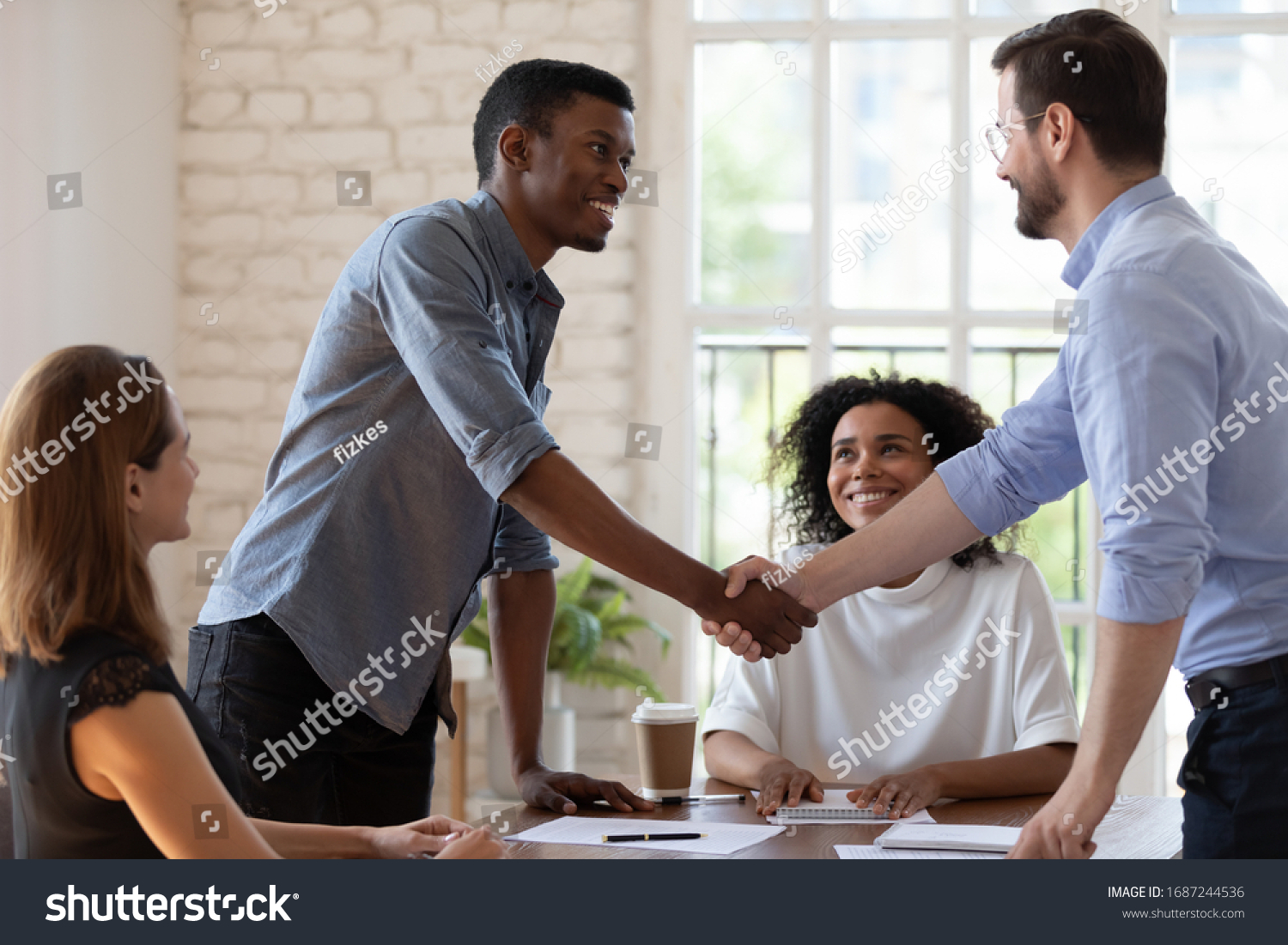 Before start negotiations African and Caucasian businessmen partners greets each other shake hands express respect friendly attitude. Closing deal, reach agreement, congratulate to promoted employee #1687244536
