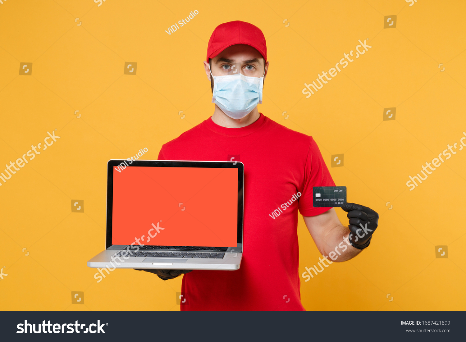 Delivery man in red cap blank t-shirt uniform mask gloves isolated on yellow background studio Guy employee work hold laptop computer Service quarantine pandemic coronavirus virus 2019-ncov concept #1687421899