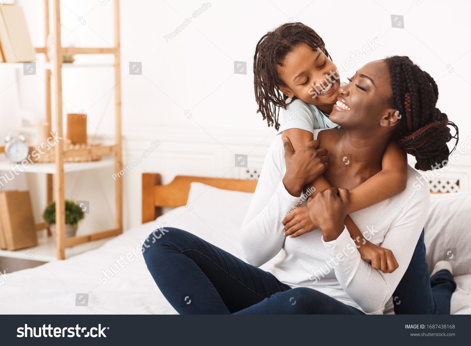 Togetherness Concept. African daughter hugging her mum from the back, sitting on bed, showing her love, empty space #1687438168