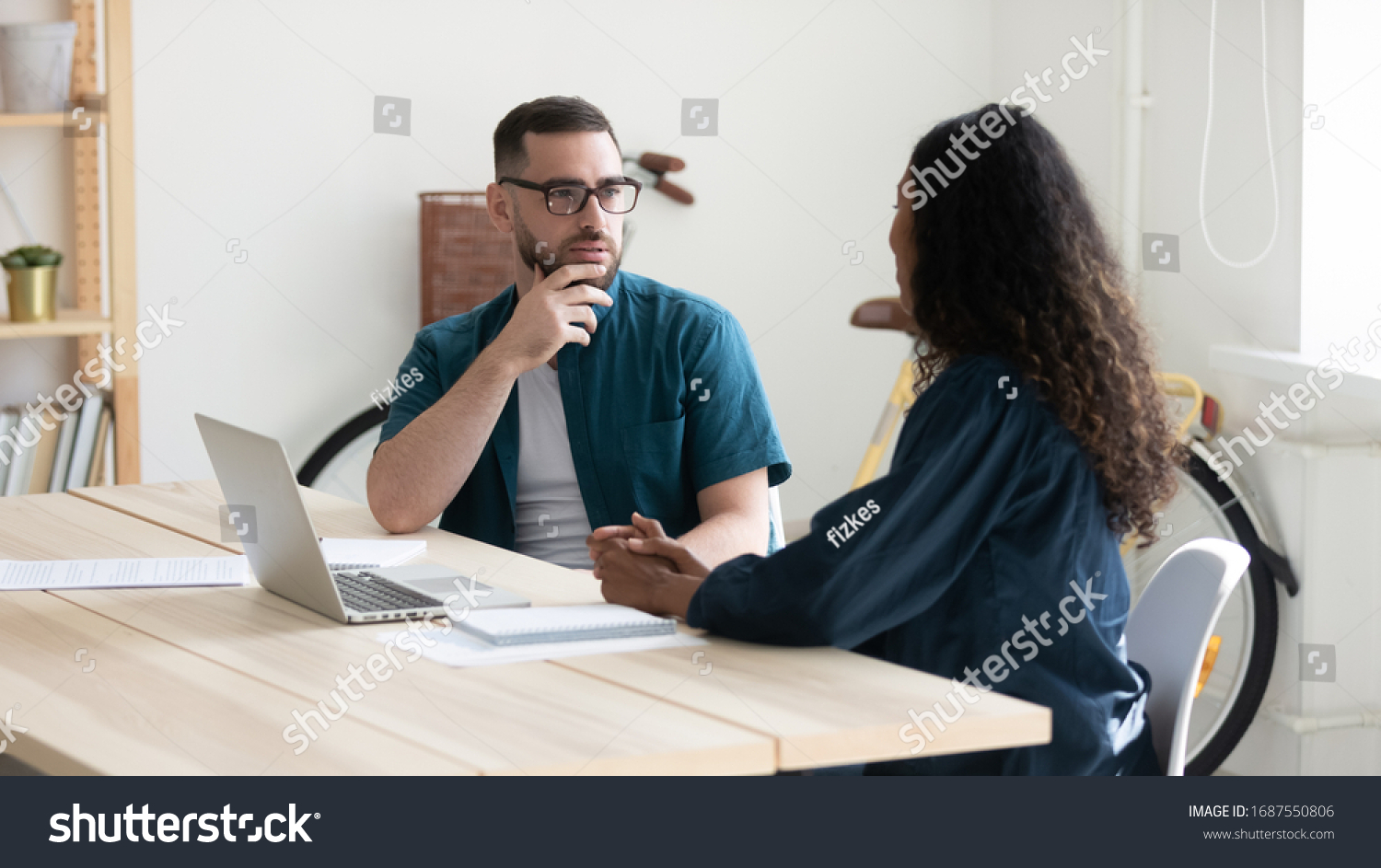 Thoughtful diverse colleagues sit at desk in office talk discuss business ideas at briefing together, pensive businesspeople brainstorm cooperate using laptop at meeting, collaboration concept #1687550806