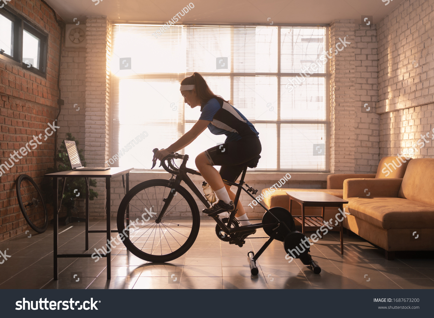 Asian woman cyclist. She is exercising in the house.By cycling on the trainer and play online bike games #1687673200