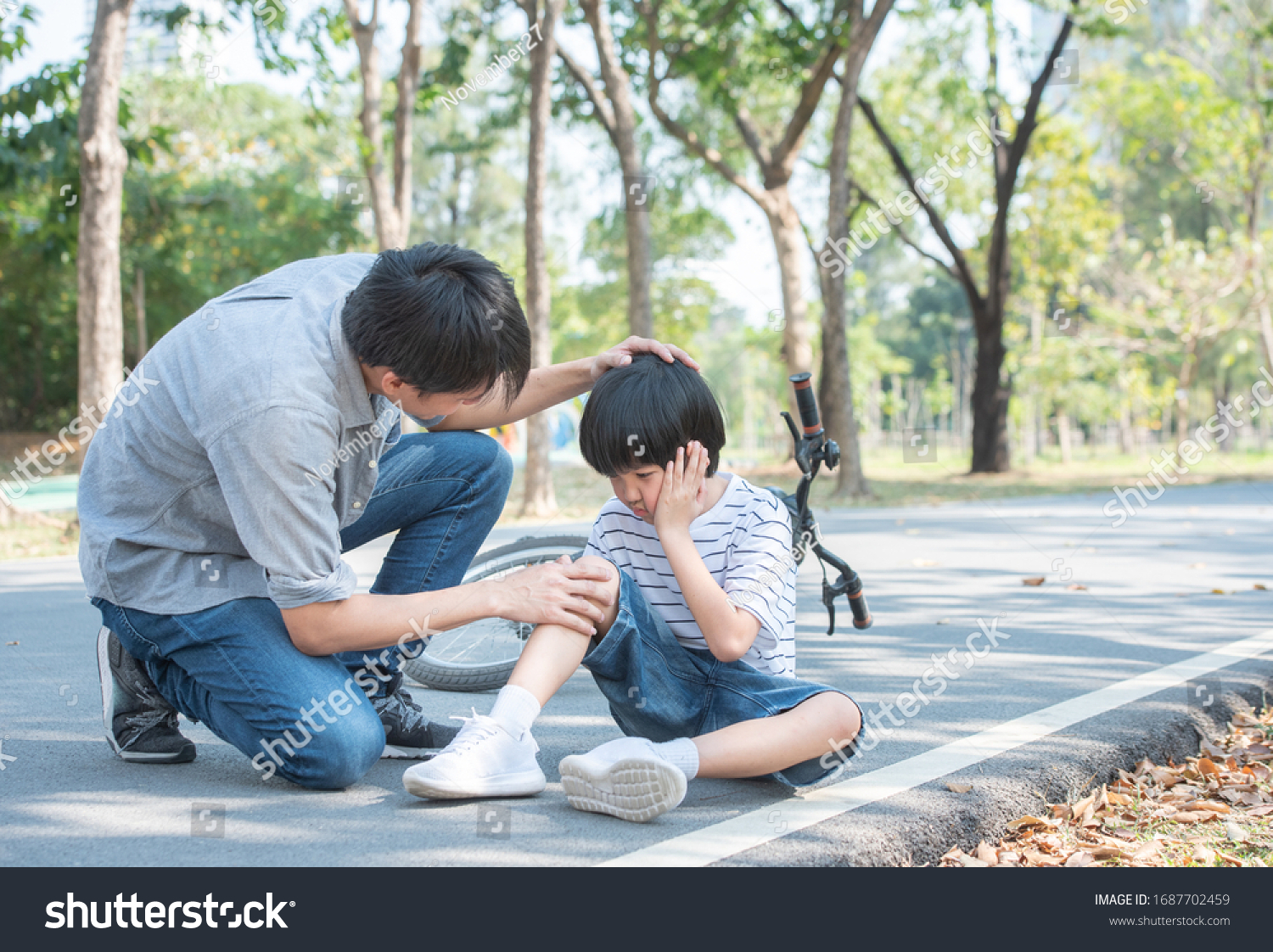 Young asian father of dad calms son that fell from the bike and he get injury on knee and leg while have weekend leisure in public park,accident can happen everywhere and every time. #1687702459
