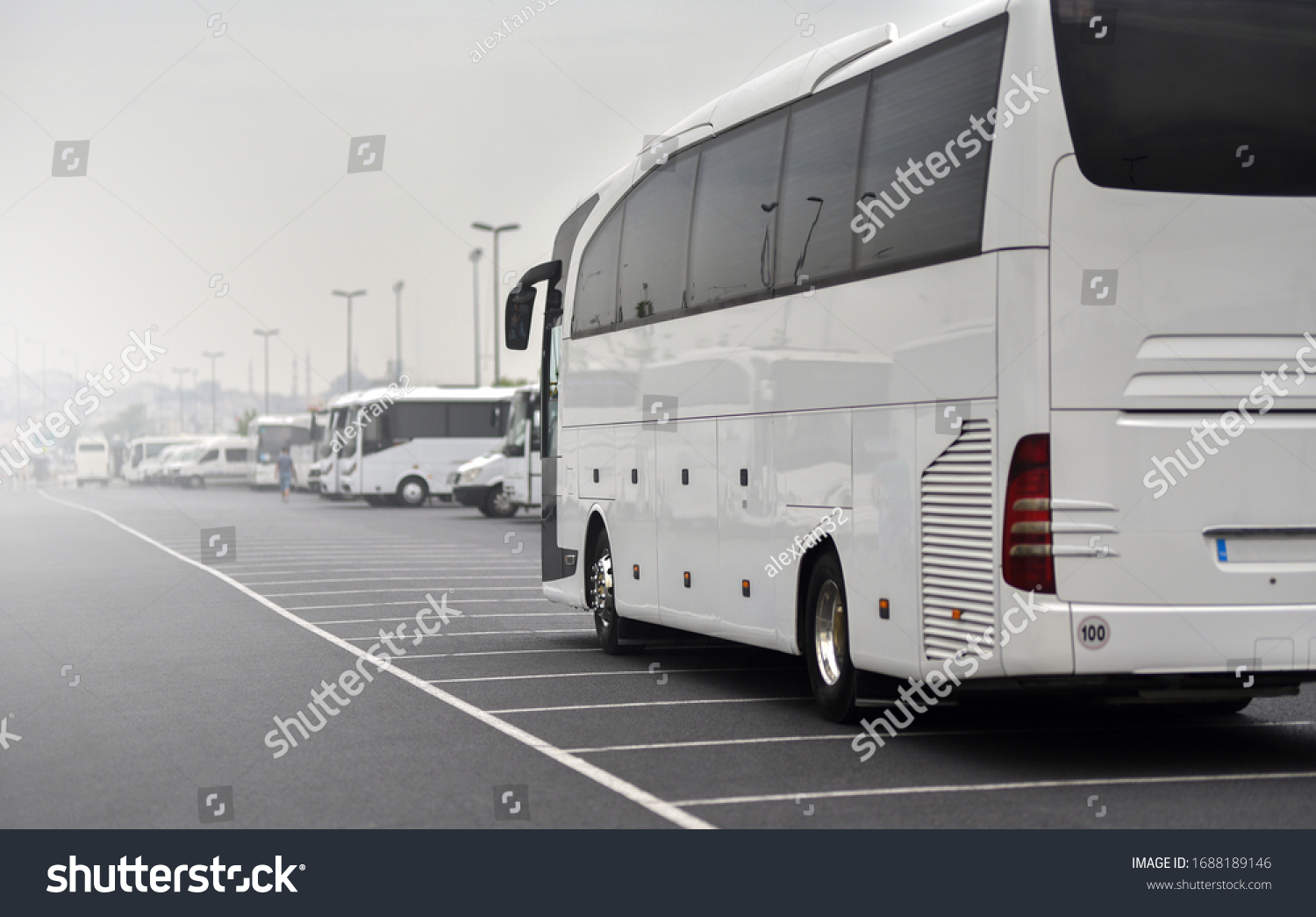 large tour bus rides along parked minibuses #1688189146