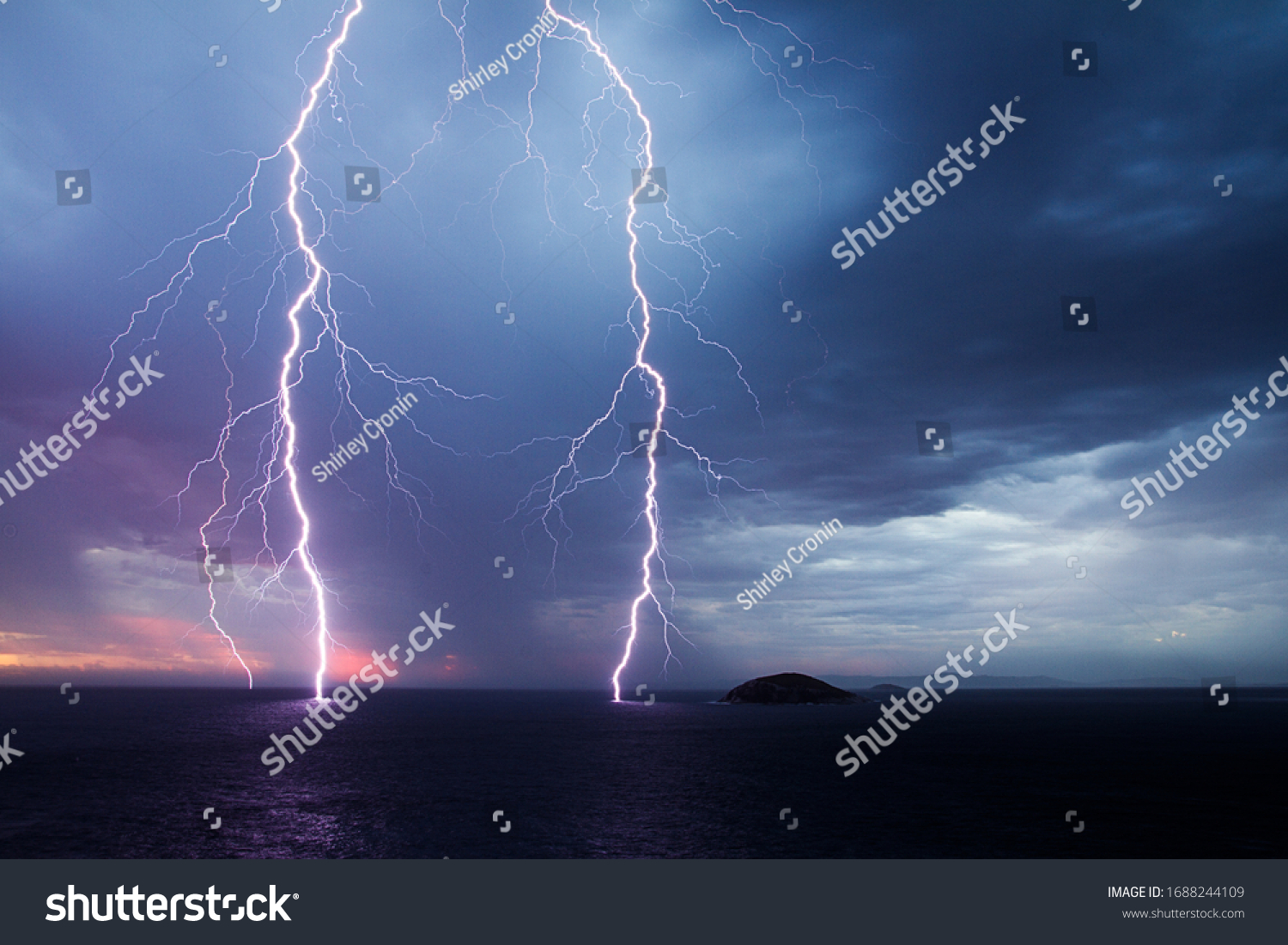 Double lightning strike over the ocean at sunset #1688244109