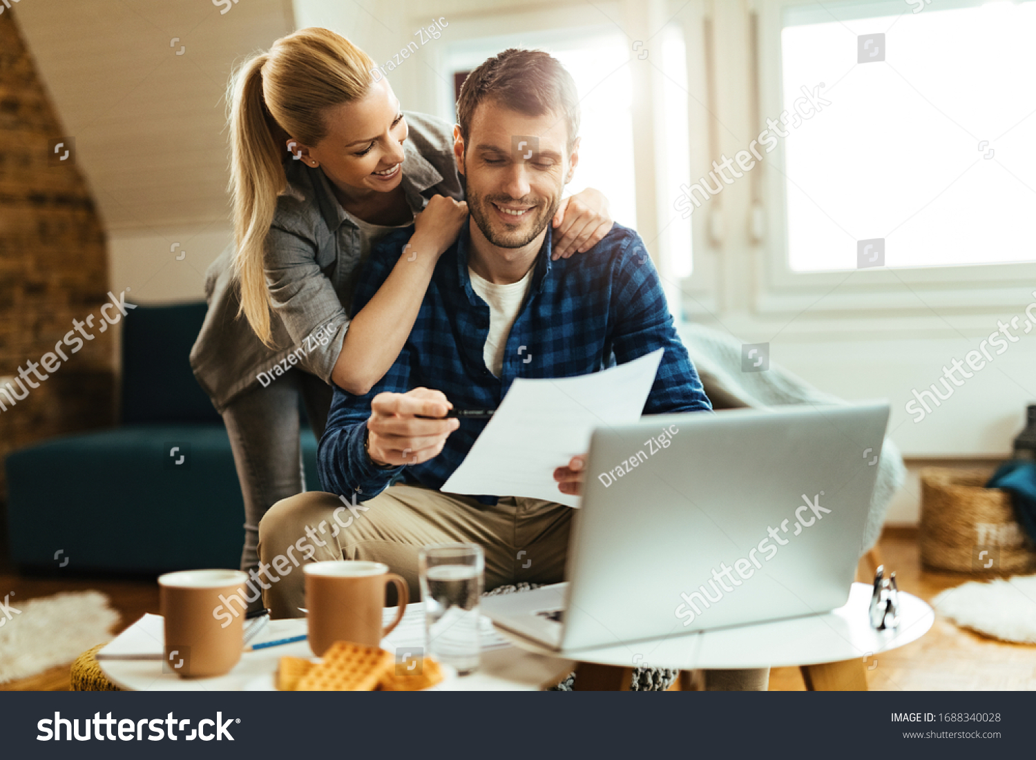 Happy couple analyzing their home budget while paying bill on a computer.  #1688340028