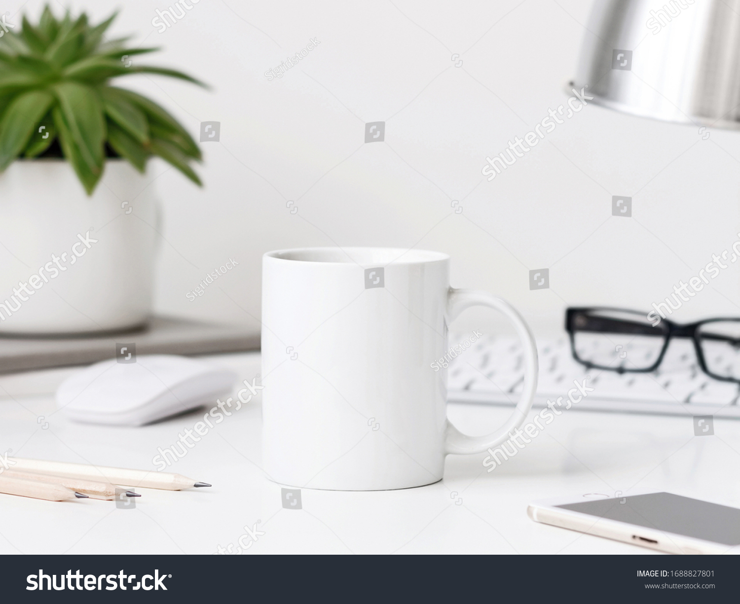 White mug mockup on workdesk with keyboard desk lamp, mouse and pencils #1688827801