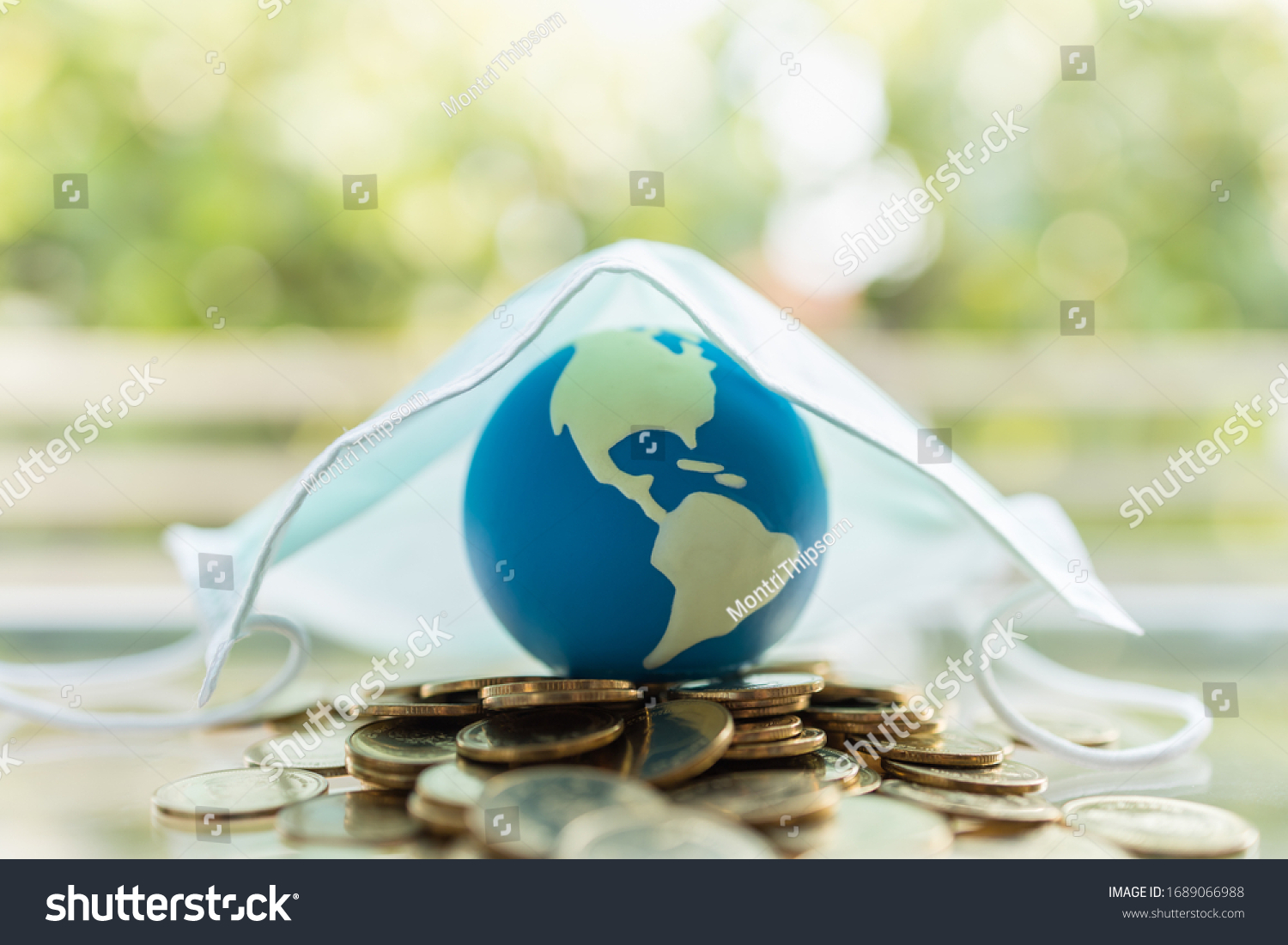 Global Money, Business, Healthcare in Cornavirus (COVID-19) Situation Concept. Mini world ball on pile of gold coins under surgical face mask with copy space. #1689066988