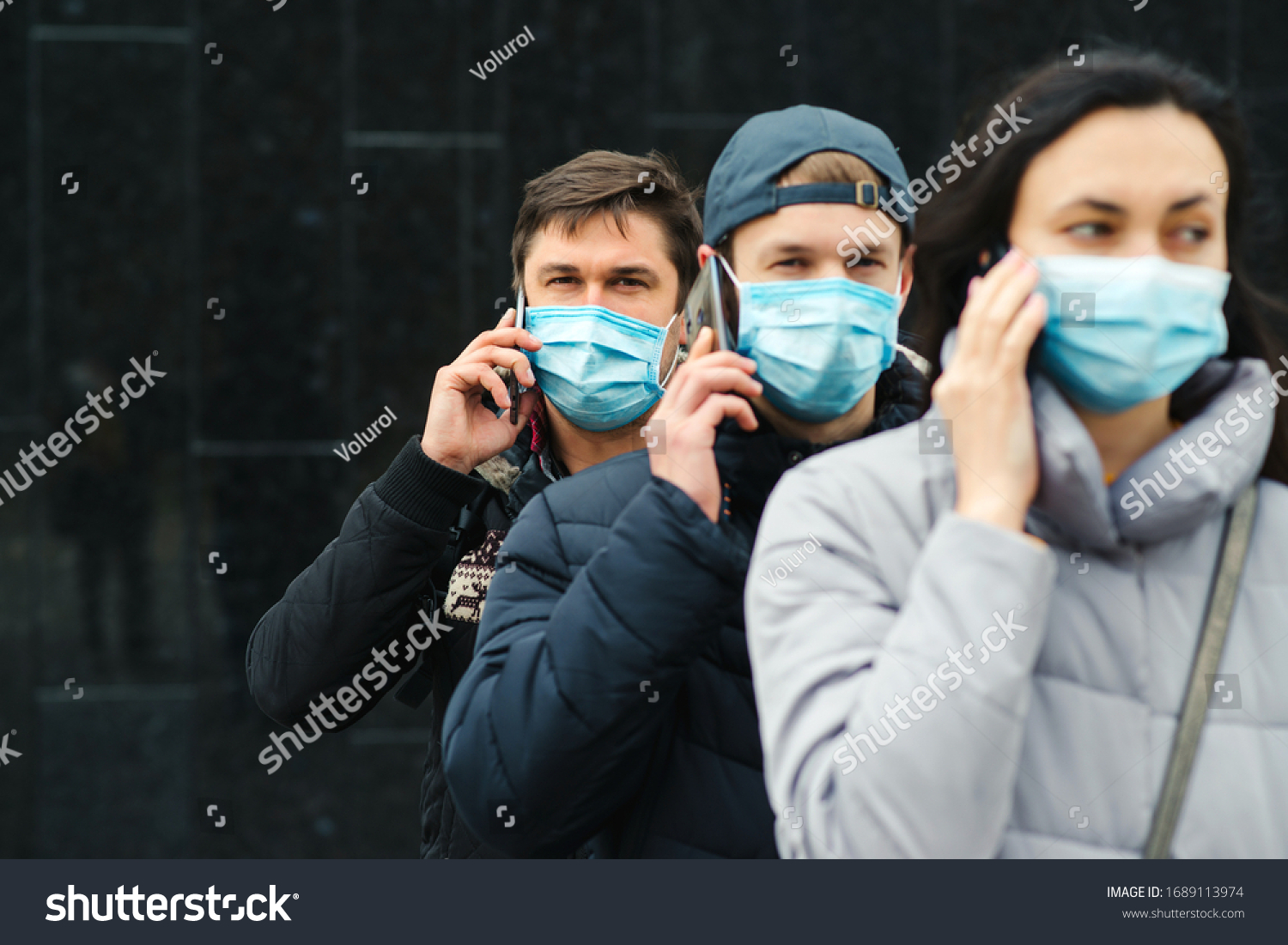Group of young volunteers wearing face masks with mobile phones. Volunteers are ready to help. Call to volunteers. The concept of mutual assistance and support. World coronavirus pandemic. #1689113974