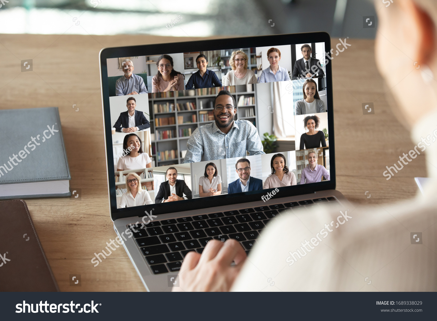 Back view of female employee speak talk on video call with diverse multiracial colleagues on online briefing, woman worker have Webcam group conference with coworkers on modern laptop at home