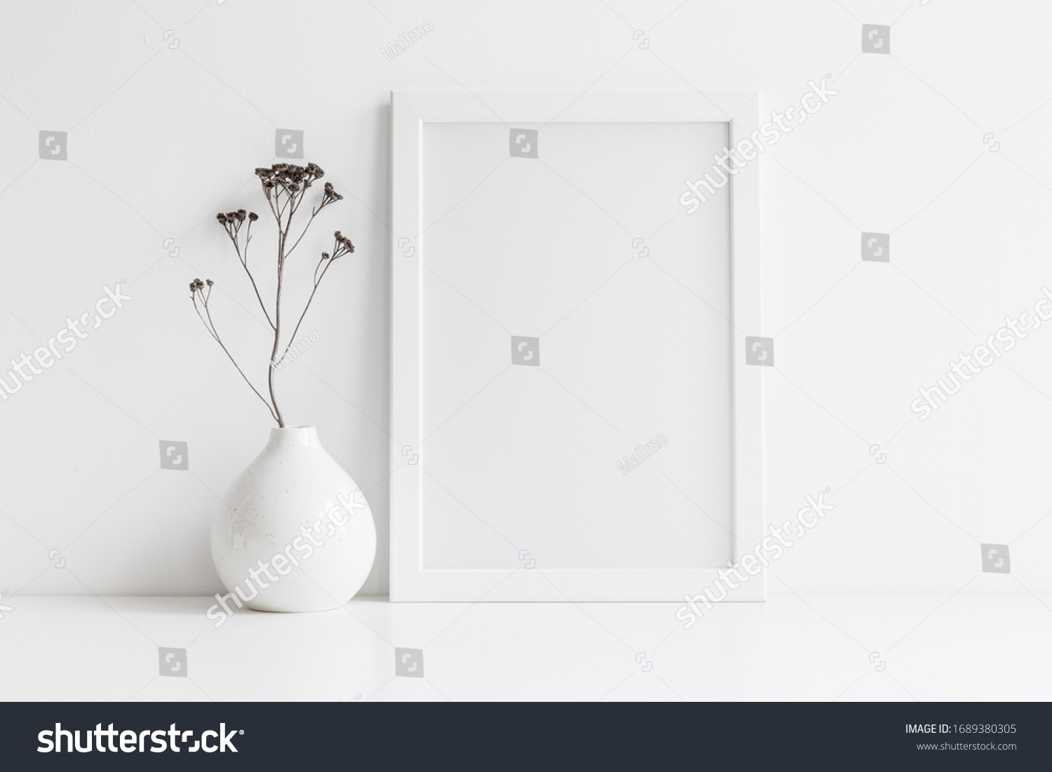 White desk with photo frame and  minimal round vase with a decorative twig against white wall.  #1689380305