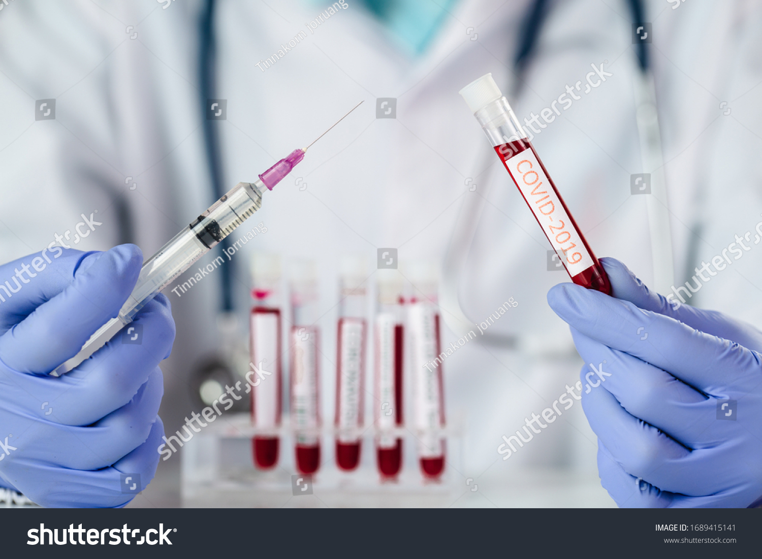 The doctor holding a vaccine to prevent the Covid-19 virus and test tube with blood sample for COVID-19 test, novel coronavirus 2019.  #1689415141