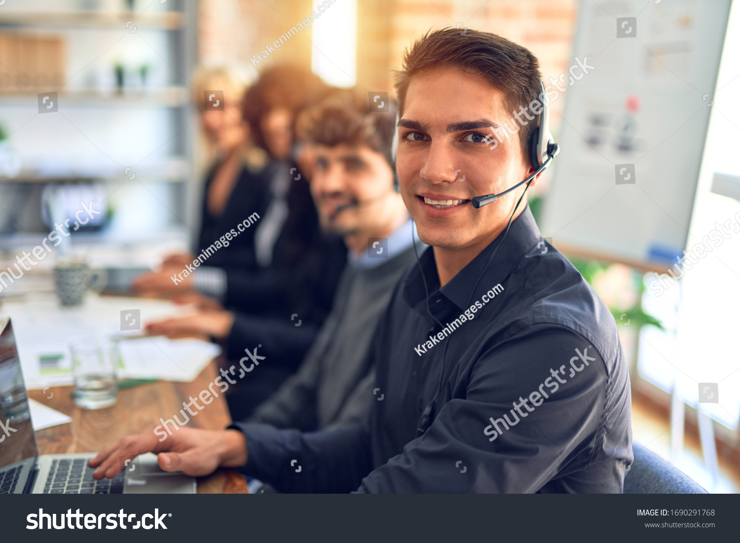 Group of call center workers working together with smile on face using headset. Young handsome man smiling at the office. #1690291768