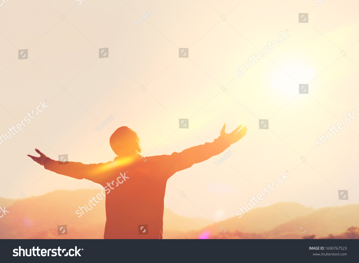 Copy space of man hand raising on top of mountain and sunset sky abstract background. Freedom travel adventure and business victory concept. Vintage tone filter effect color style. #1690767523
