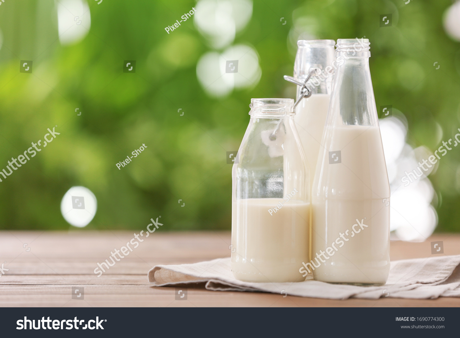 Bottles of fresh milk on table outdoors #1690774300