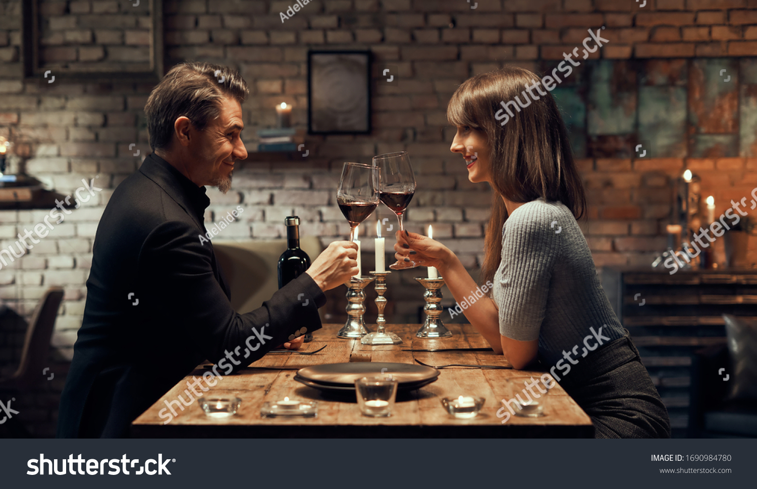 Cheerful happy couple drinking wine and having romantic dinner at home. Home date night, clinking wine glasses. #1690984780