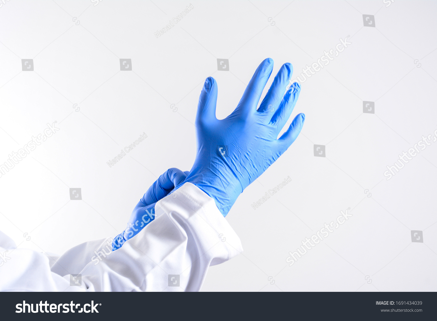 Doctor putting on sterile gloves isolated on white. scientist wearing glove. Human wearing glove on white background. blue rubber glove on a man hand isolated on white #1691434039