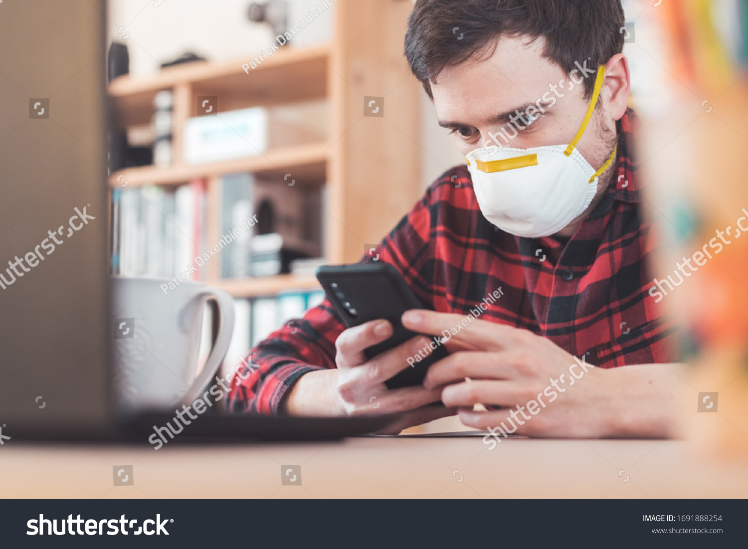Young man waring face mask is working in the office during corona crisis #1691888254