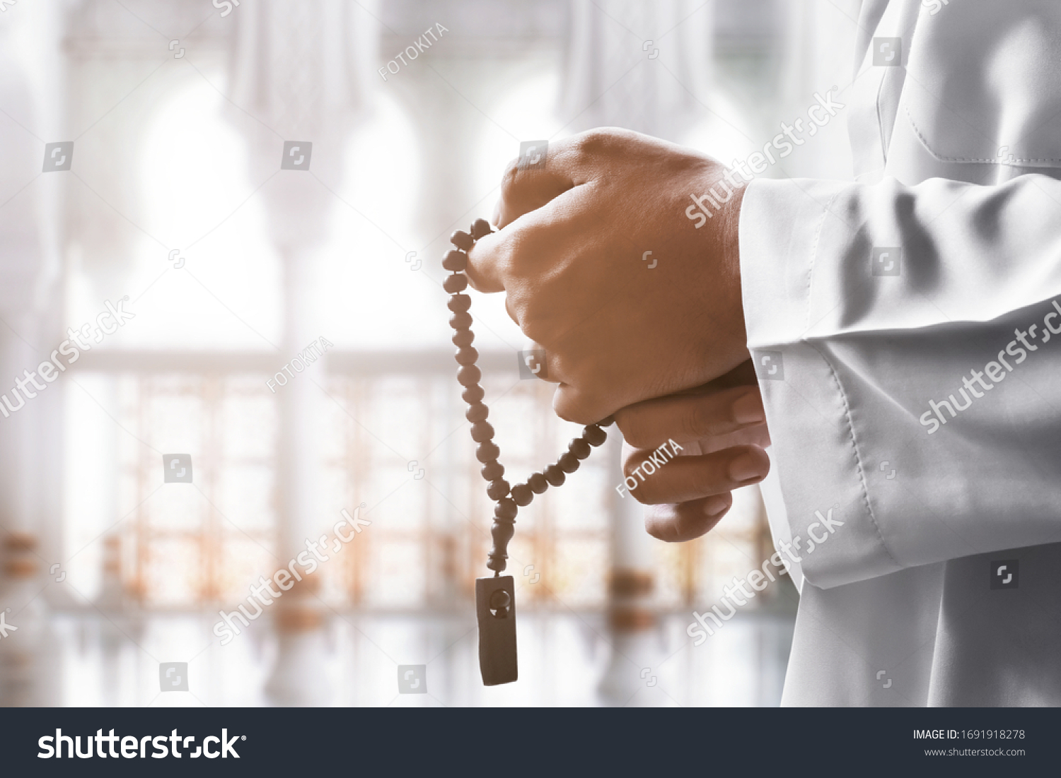Religious muslim man praying with rosary beads #1691918278