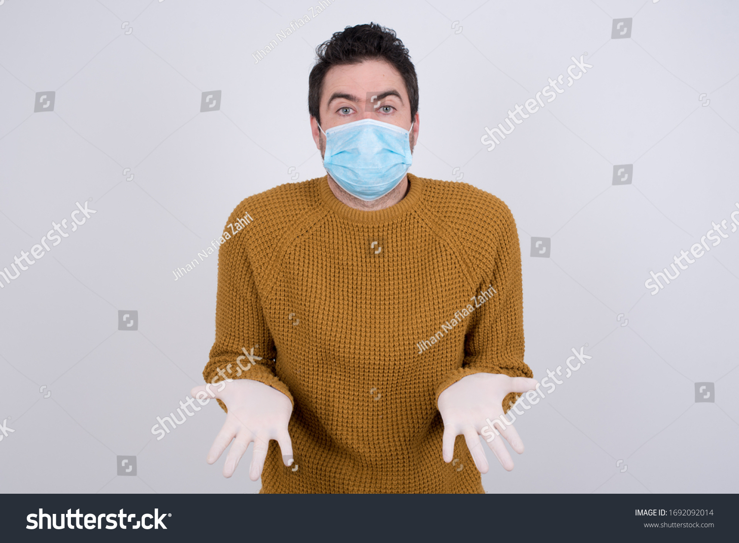 Puzzled and clueless young man with arms out, shrugging his shoulders, saying: who cares, so what, I don't know. Protection against infectious diseases. #1692092014