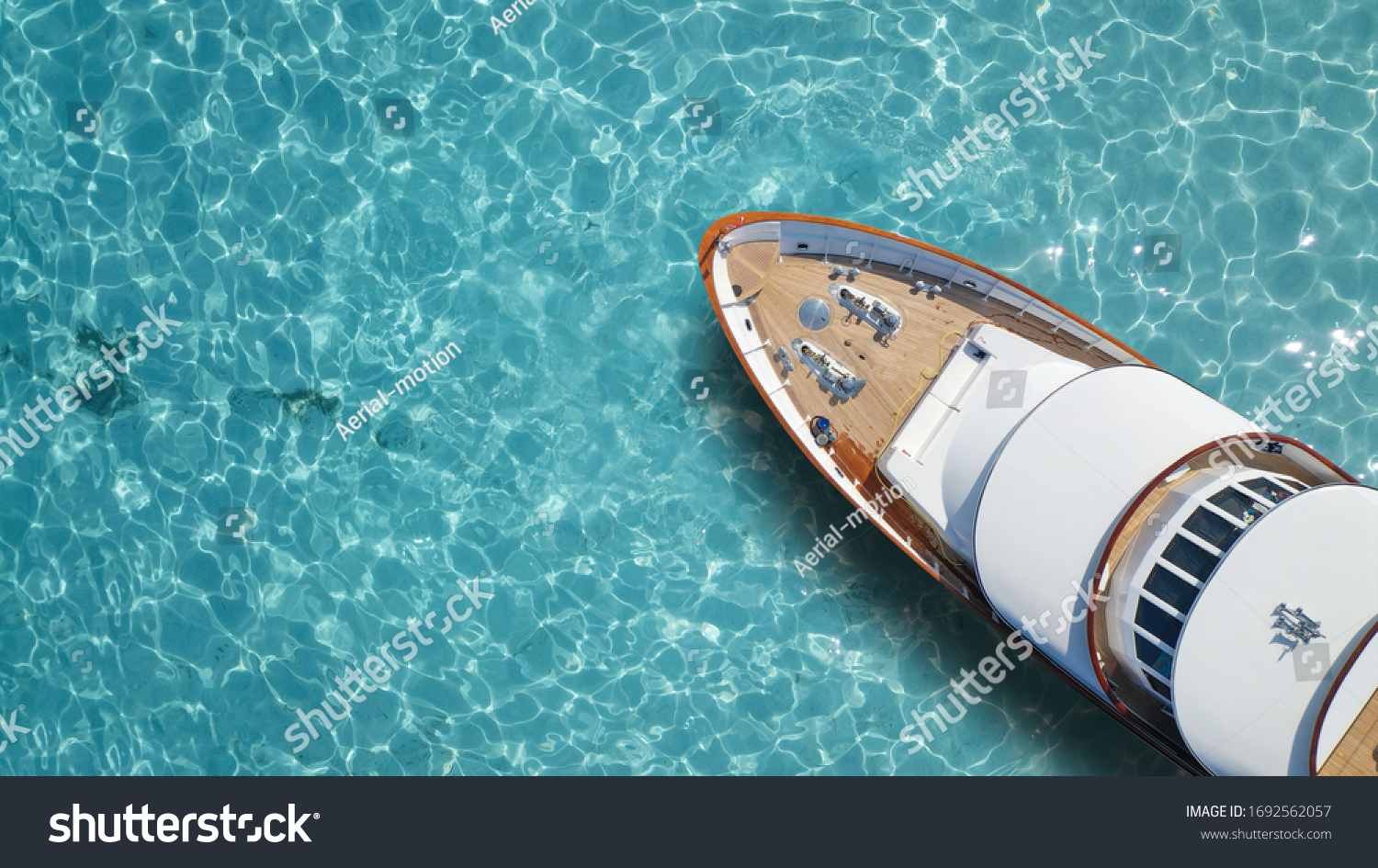 Aerial drone top down photo of luxury exotic yacht nose with wooden deck anchored in paradise turquoise bay #1692562057