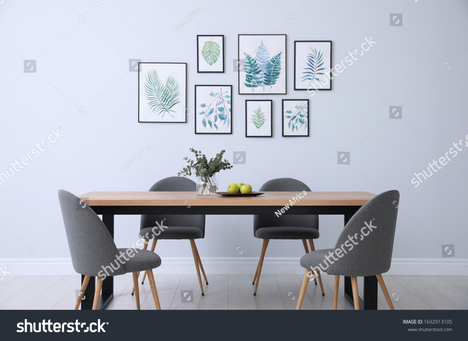 Stylish room interior with modern table, chairs and paintings of tropical leaves. Idea for design #1692913105
