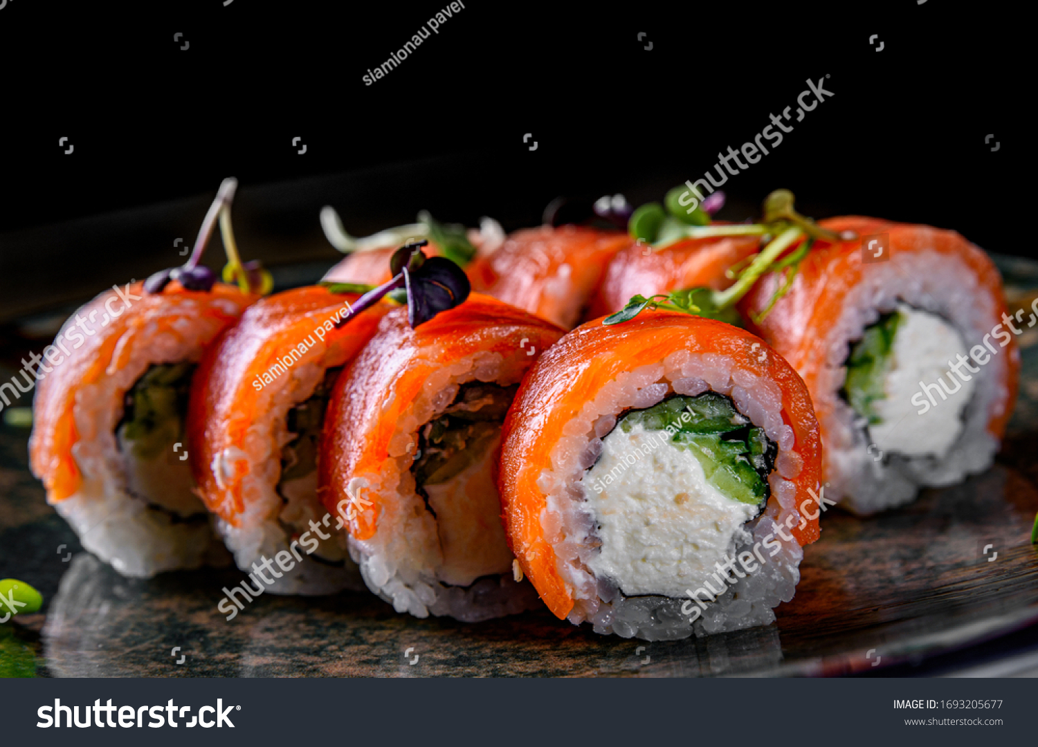 sushi roll with salmon, avocado, cream cheese in plate on black wooden table background #1693205677