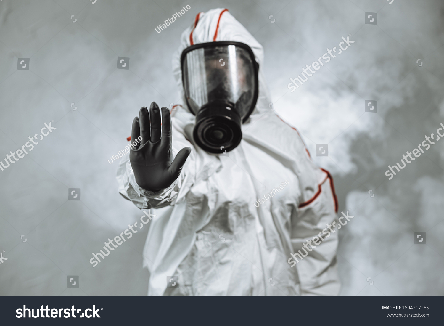 keep the distance, stop to coronavirus. disinfector male in gas-mask and protective suit disinfect contaminated areas full of bacterias. quarantine time #1694217265