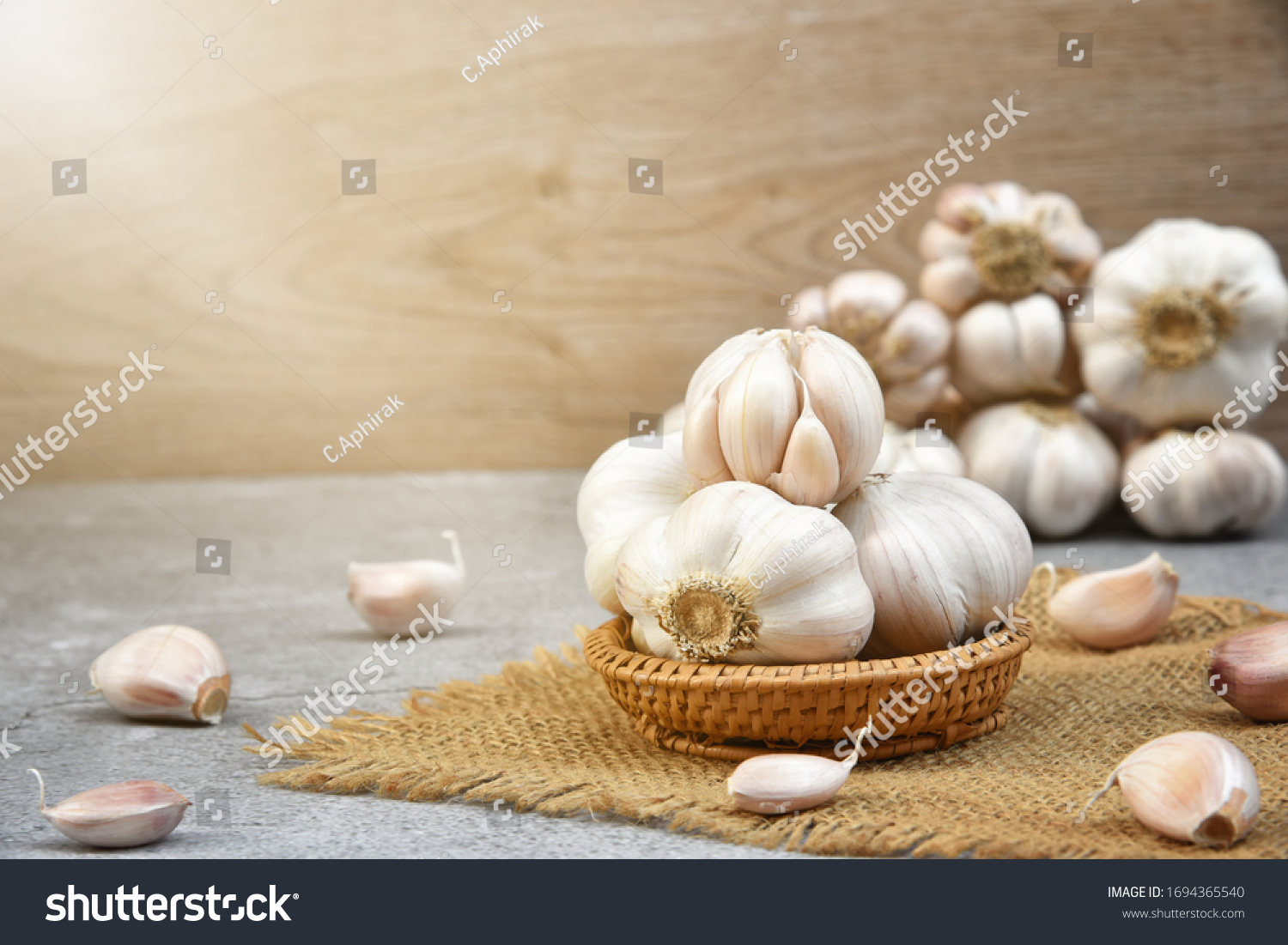 Organic Garlic. Fresh Garlic Cloves and Garlic bulb in wooden basket on dark background with Pile of garlic or spice. Selected focus. Concept of spices for healthy cooking. #1694365540