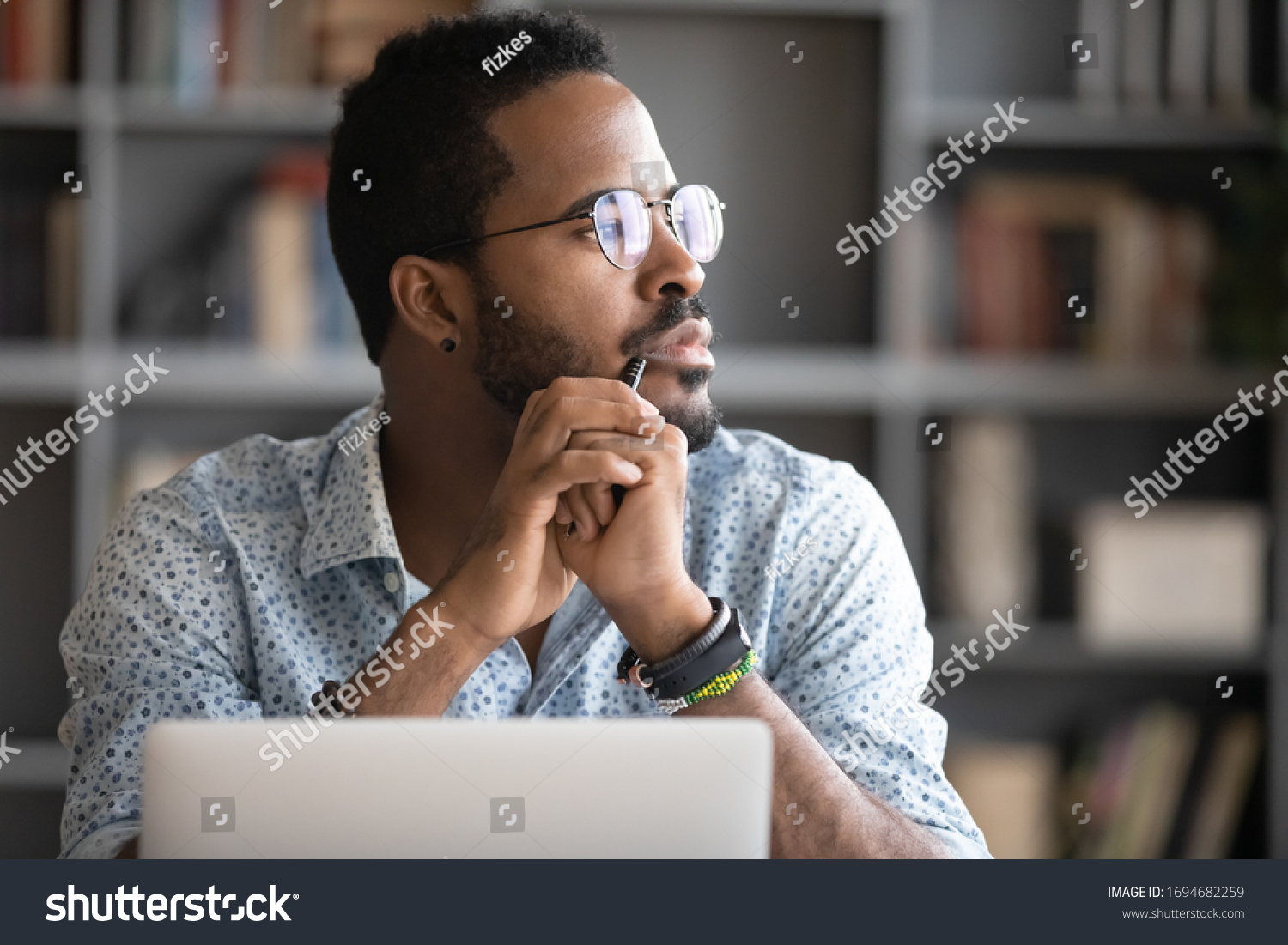 Pensive African American man in glasses distracted from computer work look in distance thinking or pondering, thoughtful biracial male lost in thoughts make plans visualizing, business vision concept #1694682259