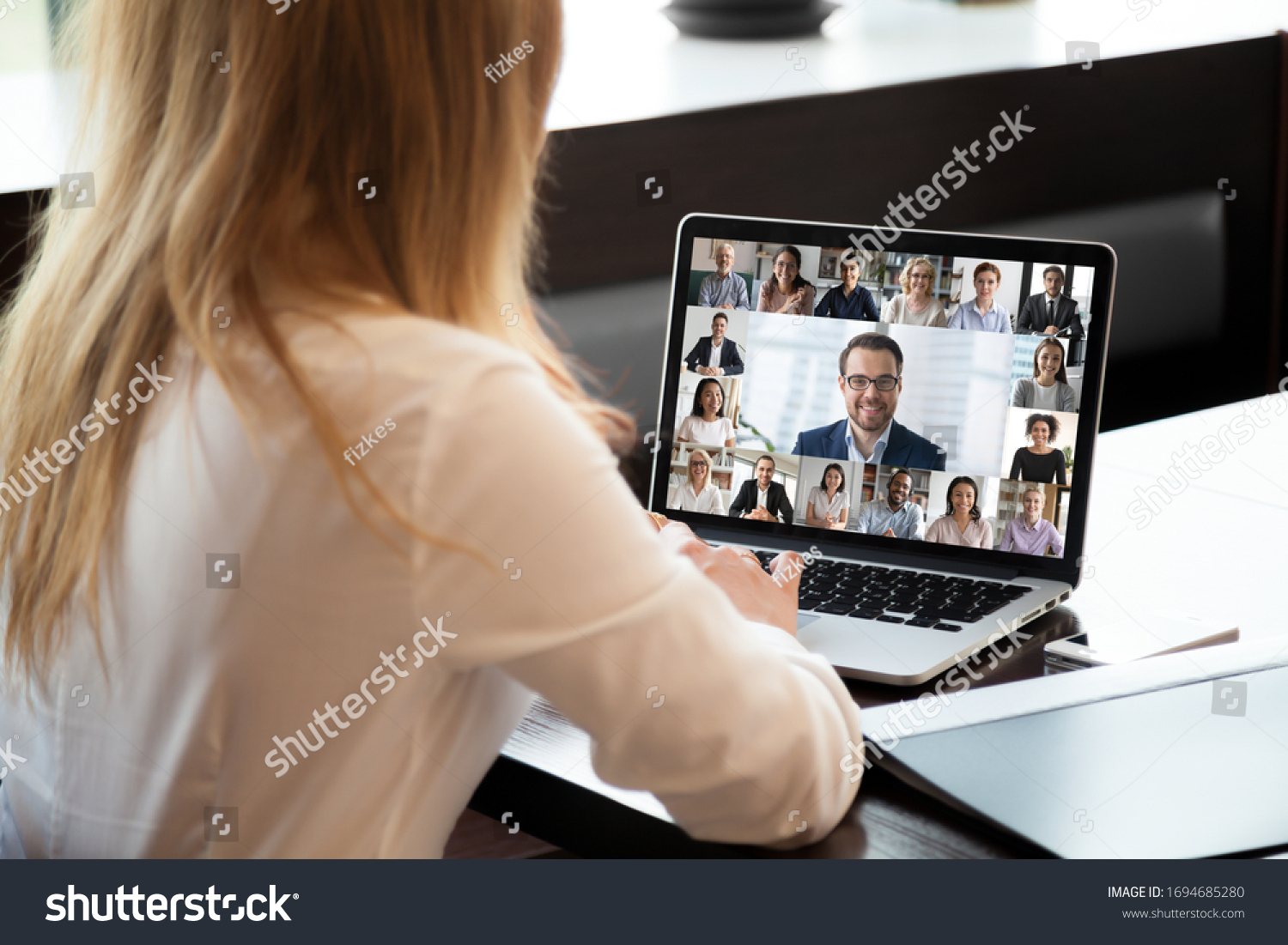 Pc screen view over woman shoulder at group video call. Visual communication between engaged diverse people distantly using webcam and laptop internet connection app. International remote chat concept #1694685280