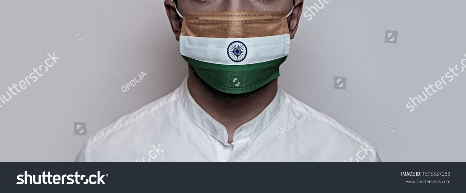 Corona virus pandemic. Concept of Corona virus quarantine, Covid-19. The male face is covered with a protective medical mask, painted in India flag colors #1695537283