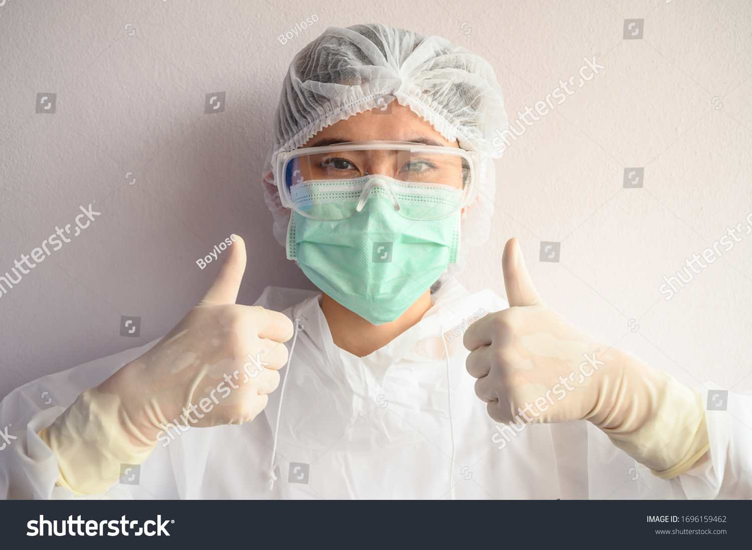 Nurse wearing PPE suit with mask for protect virus and showing thumbs up. In coronavirus pandemic outbreak we should support and encourage healthcare worker by stay home and listen to medical advice. #1696159462