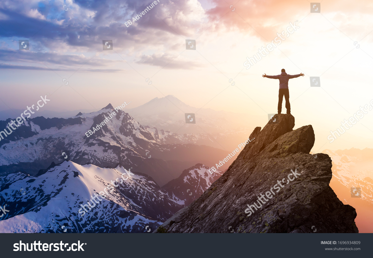 Adventure, Explore and Lifestyle Concept Composite. Adventurous Man Hiker With Hands Up on top of a Steep Rocky Cliff. Sunset or Sunrise. Landscape Taken from Washington, USA. #1696934809