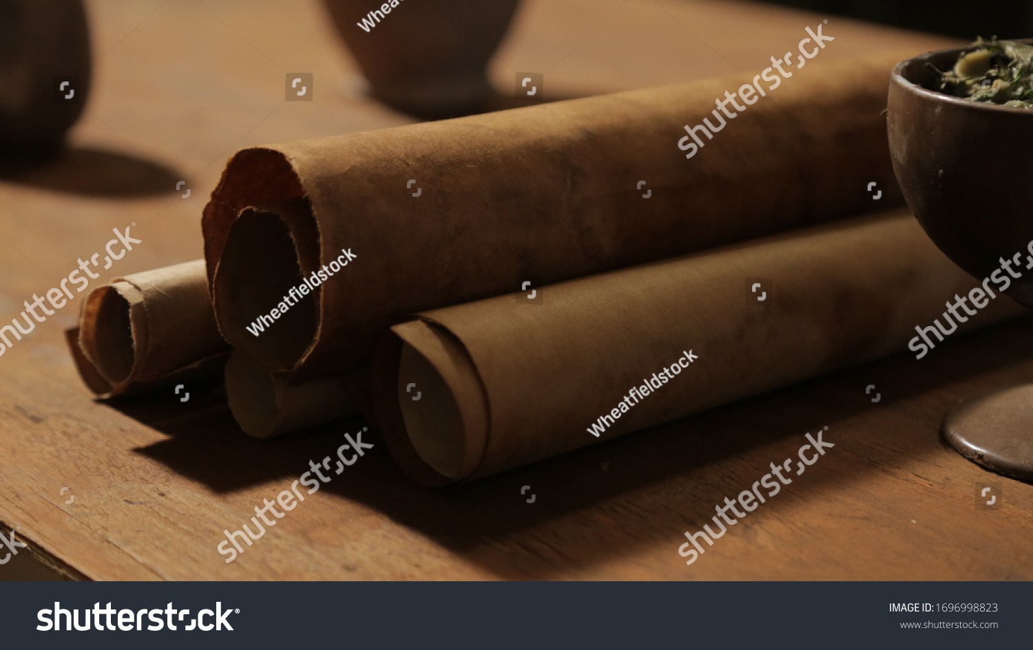 Bible scene: a wooden dining table with scripture scrolls. Close-up of rolls of old paper, cup with food. #1696998823