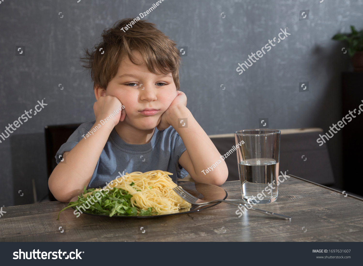 The child doesn't want to eat. The boy eats spaghetti. Poor appetite. Healthy diet. Refuses to eat. A disgruntled child at lunch. #1697631607