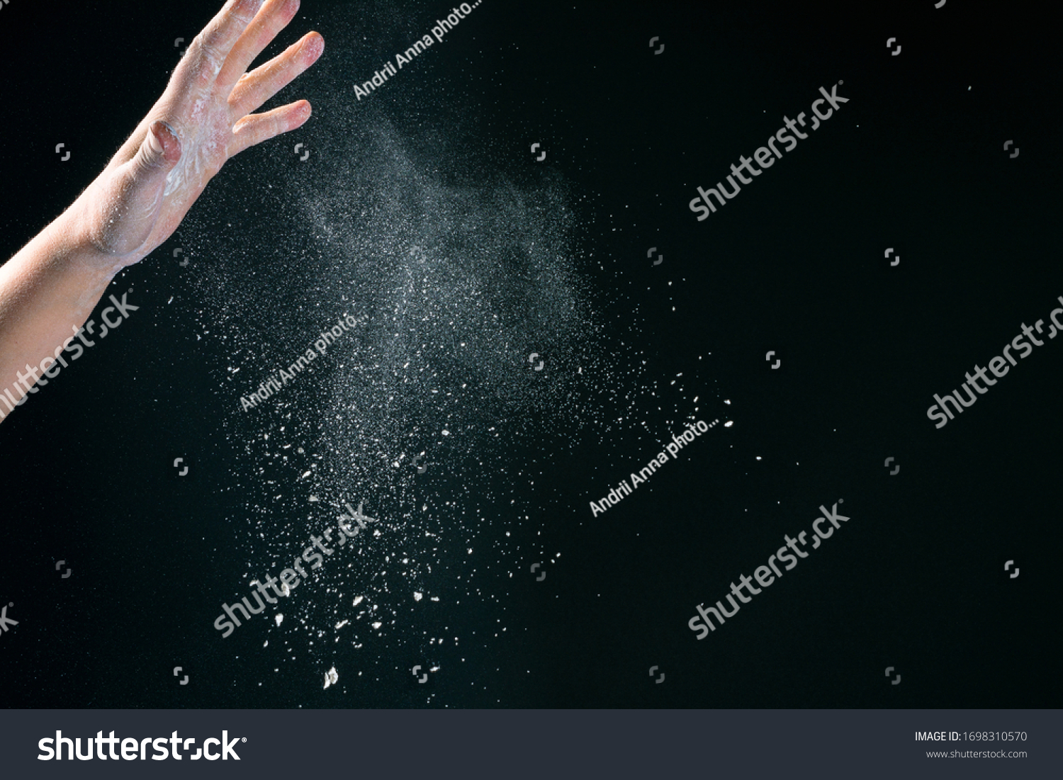 Hand of european woman chef in kitchen pouring flour on black background #1698310570