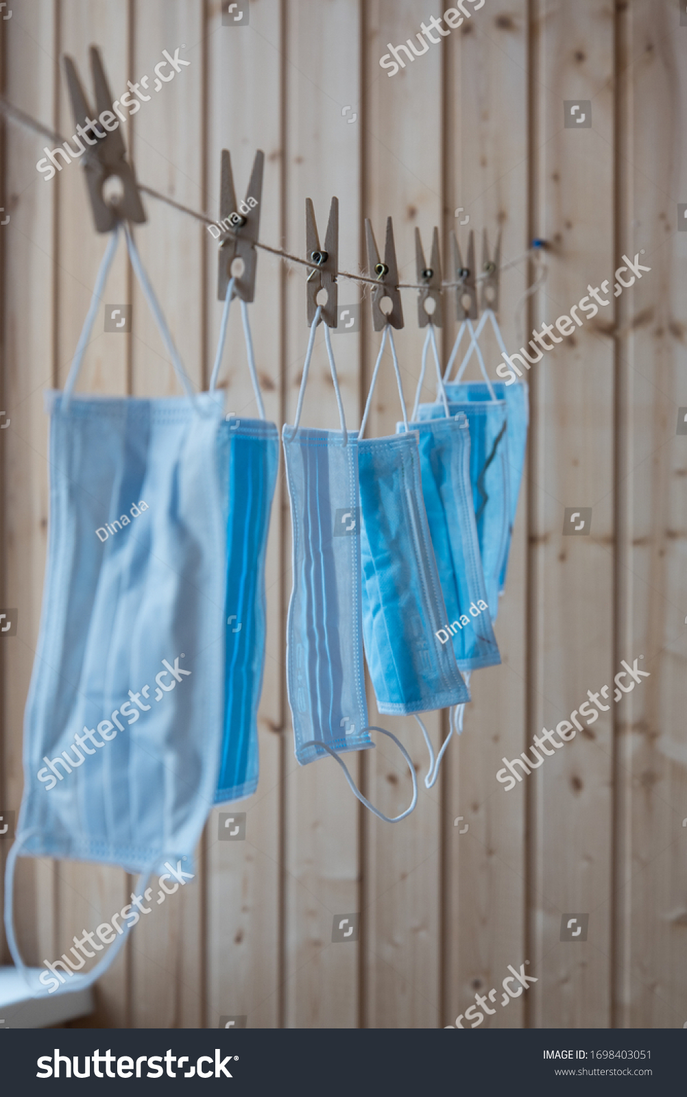 Disposable medical masks hang on a clothesline. Concept. Reuse. Deficit #1698403051