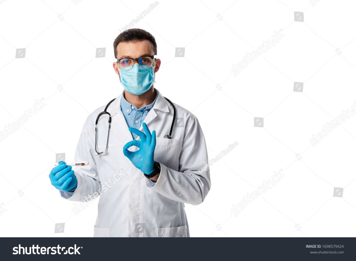 doctor in medical mask and white coat holding digital thermometer and showing ok sign isolated on white #1698579424
