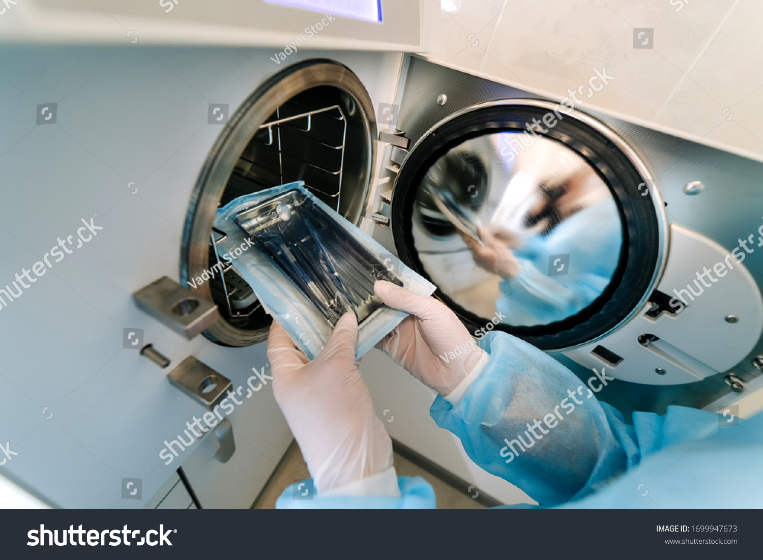 Female nurse doing sterilization of dental medical instruments in autoclave. Sterilization department at dental clinic #1699947673