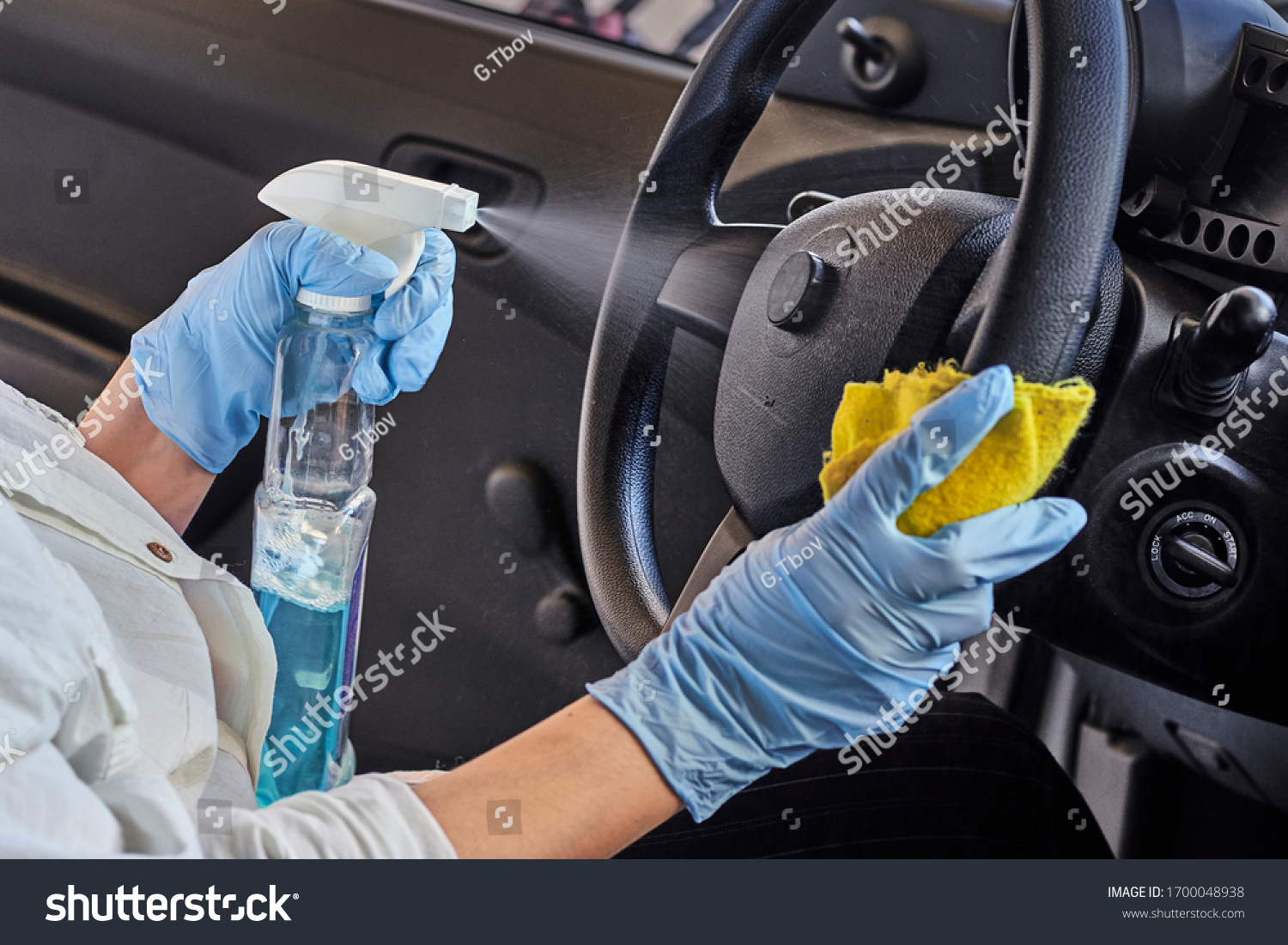 Woman in rubber protective glove disinfecting car steering wheel. Cleaning vehicle inside for protection from Coronavirus disease. Epidemic Outbreak