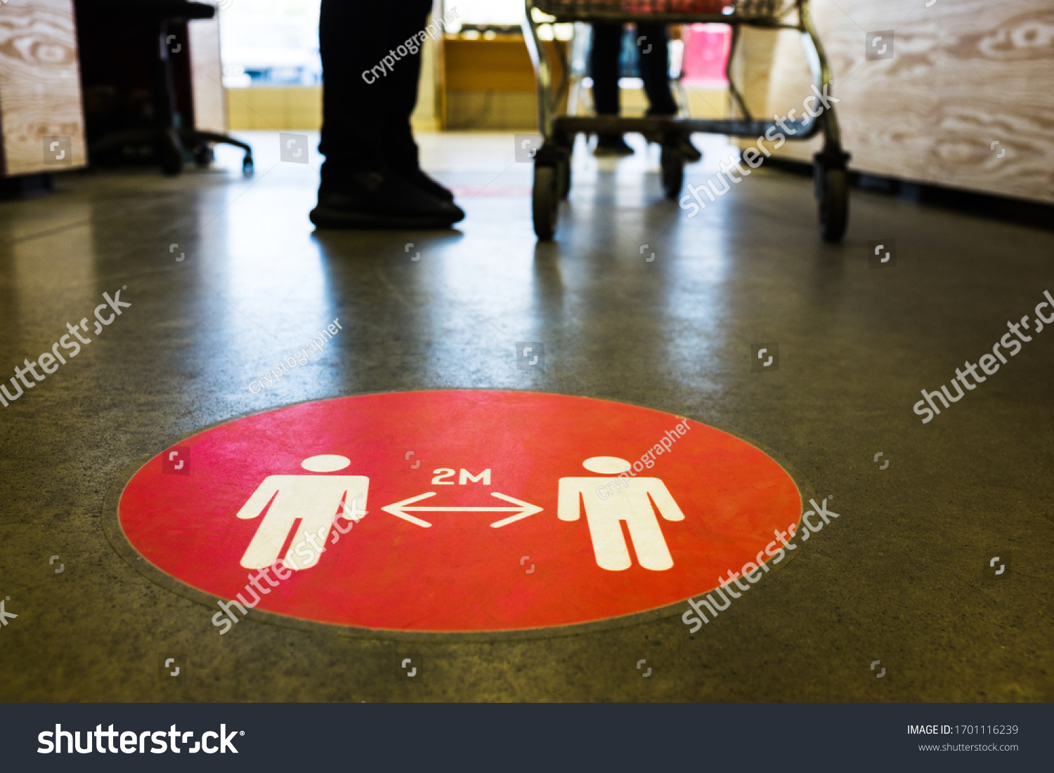 Red round sign printed on ground at supermarket cash desk register informing people to keep 2 meter 6 feet distance from each other,prevent spreading Coronavirus COVID-19 virus disease infection,UK&US