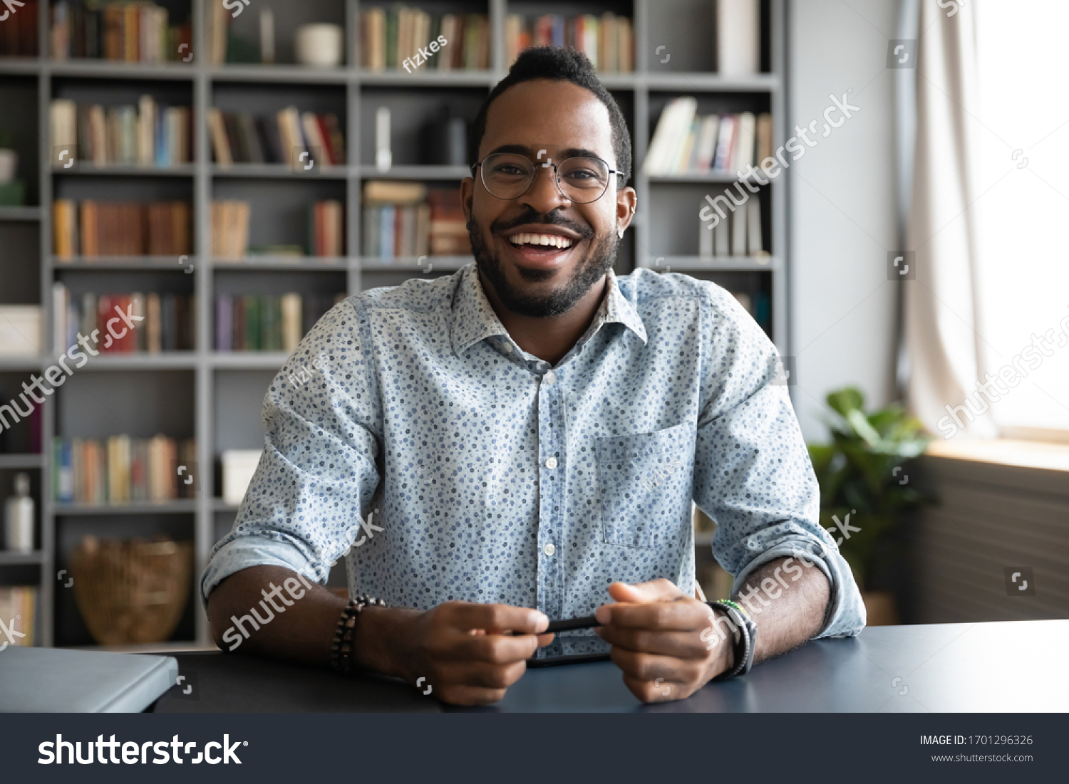 Headshot portrait of happy african American man in glasses sit at desk have video call on gadget, smiling biracial young male in spectacles talk speak on web, using online dating service application #1701296326